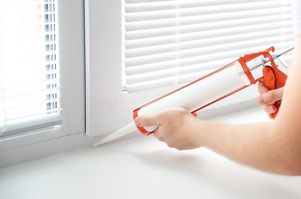 Construction worker use gun silicone tube for repairing and installing window in house