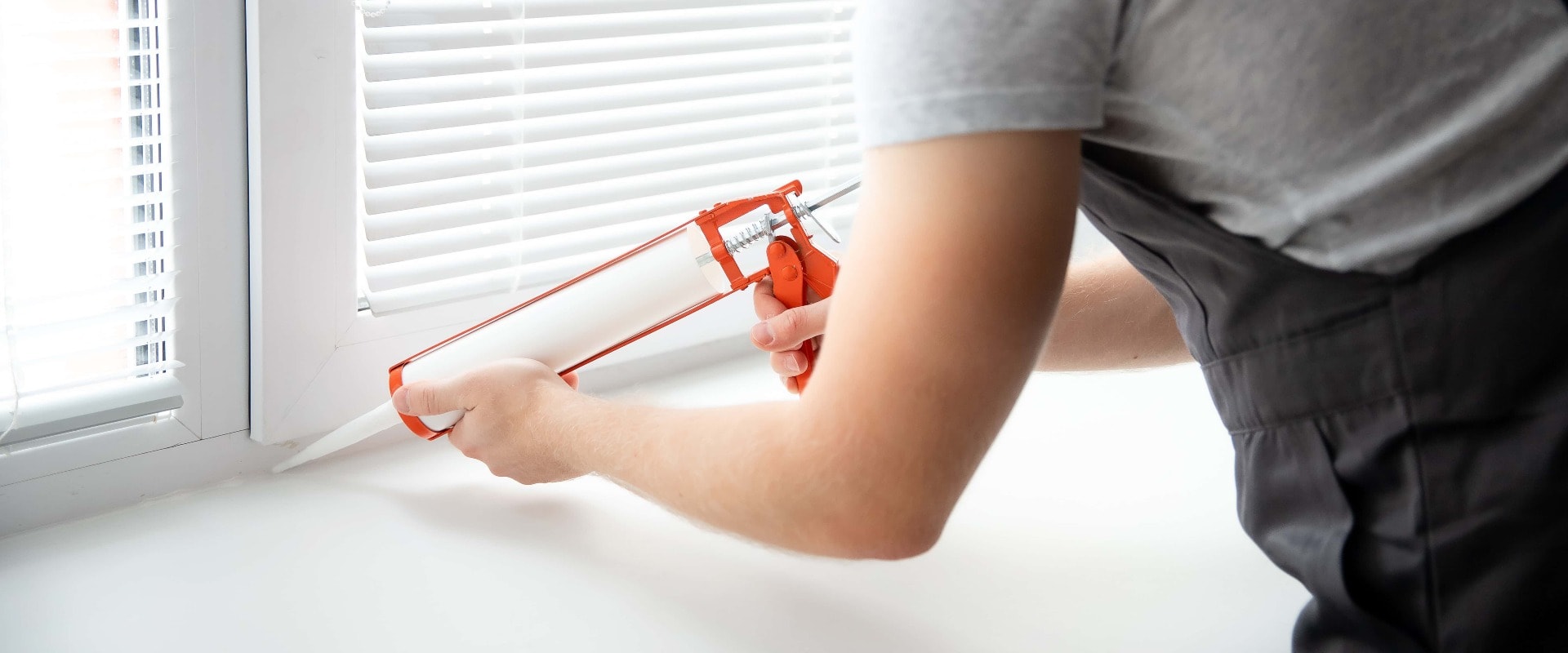 Construction worker use gun silicone tube for repairing and installing window in house