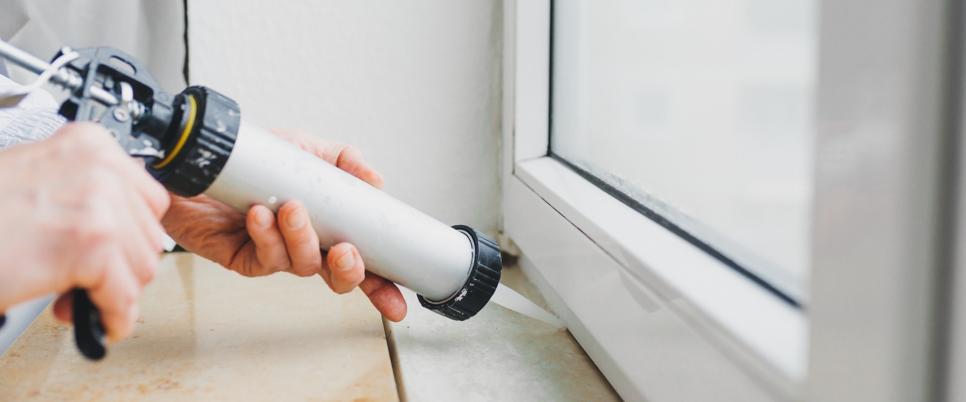 Hands of worker using a silicone tube  for repairing of window