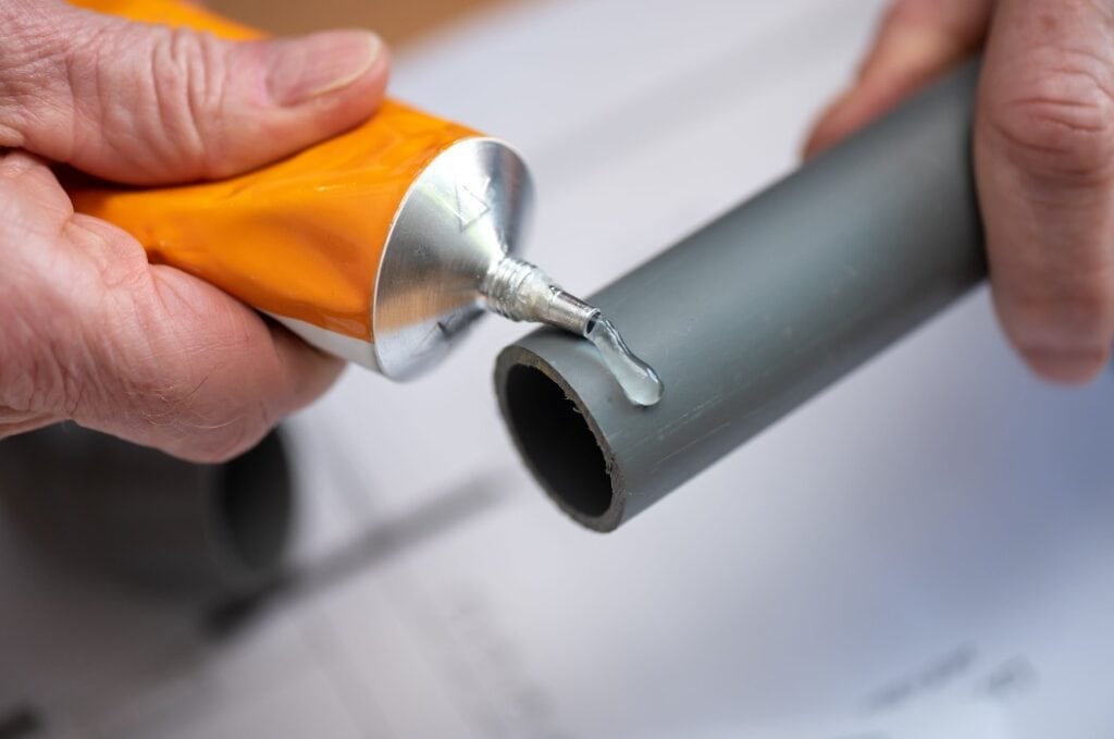 Plumber applying glue on pvc pipe