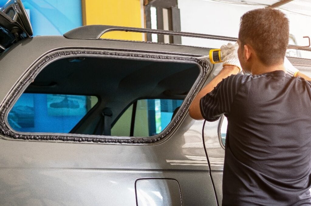 Technicians are using silicone to install the right rear glass of the car.